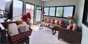 a living room with two couches and a tv at TUK&TOON House in Sathani Ban Thap Chang
