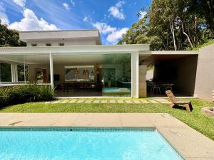 a house with a swimming pool in front of a house at Casa 10 Floresta Boa Vista - Piscina Privativa, Adega e Conforto em 4 suítes in Teresópolis