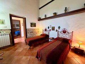 a bedroom with two beds and a stone wall at Casa Fochita in Gratteri +27 photos