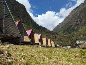 a row of houses on a hill with mountains in the background at Salkantay Star Camp Chaullay in Colcapampa
