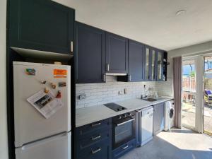 a kitchen with blue cabinets and a white refrigerator at Cosy Bungalow in Balbriggan