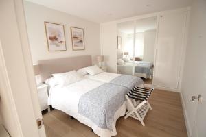 a white bedroom with a large bed and a mirror at Atardecer en el Jerte in Cabezuela del Valle +4 photos