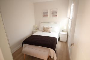a small white bedroom with a bed and two night stands at Atardecer en el Jerte in Cabezuela del Valle