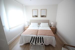 a white bedroom with a large bed and two mirrors at Atardecer en el Jerte in Cabezuela del Valle