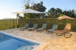 a group of chairs and an umbrella next to a pool at Villa Marko in Ljubitovica