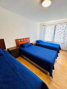 a bedroom with two beds with blue sheets and a window at Departamento Independiente Altavista Hostal- 6 personas in Rancagua +7 photos
