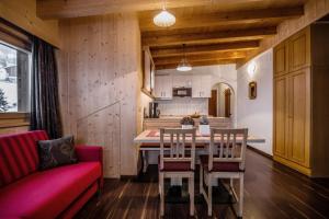 a living room with a table and a red couch at Ciasa Confolia in Corvara in Badia