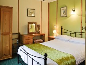 a bedroom with a large bed and a mirror at Stream Cottage - 27550 in Wheddon Cross +4 photos