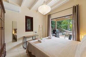 a bedroom with a large white bed and a balcony at Villa The Hidden Palm, Piscadera, Private Pool in Willemstad
