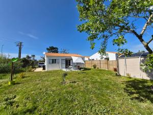 a yard with a white house and a fence at Maison neuve 3 étoiles proche de la mer in La Brée-les-Bains