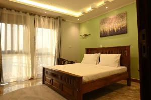 a bedroom with a bed with white sheets and a window at Neon Hotel in Kampala