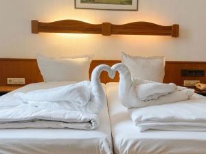 two swans are sitting on top of two beds at Hotel Restaurant Bären in Weingarten +18 photos