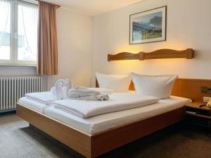 a bedroom with a large bed with white sheets at Hotel Restaurant Bären in Weingarten