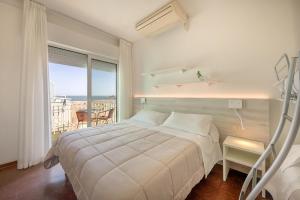a white bedroom with a bed and a balcony at Hotel Sanremo in Caorle