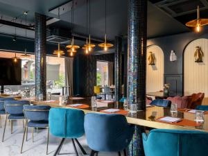 restauracja z długim stołem i niebieskimi krzesłami w obiekcie ibis Styles Hasselt City Centre w mieście Hasselt