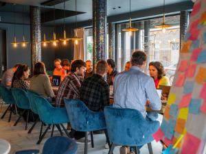 a group of people sitting at tables in a restaurant at ibis Styles Hasselt City Centre in Hasselt