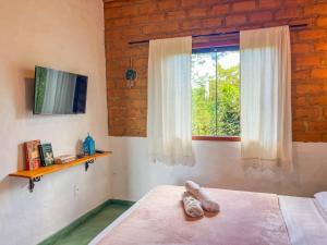 a bedroom with a window and two pairs of shoes on a bed at Sítio Embaú in Carrancas