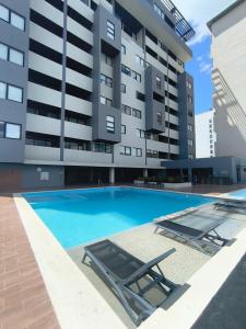 a swimming pool with two lounge chairs and a building at Buyan Departamentos in Mérida