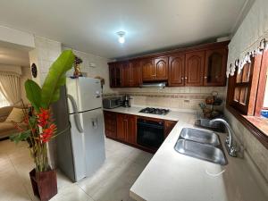 a kitchen with wooden cabinets and a white refrigerator at La muñeca Chalet in Circasia