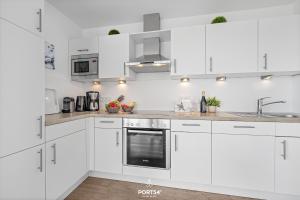 a white kitchen with white cabinets and a sink at Ferienwohnung Albatros Olpenitz in Olpenitz