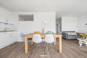 a kitchen and dining room with a wooden table and two white chairs at Ferienwohnung Albatros Olpenitz in Olpenitz