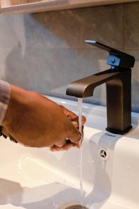 a person is washing their hands under a water faucet at Neon Hotel in Kampala +100 photos