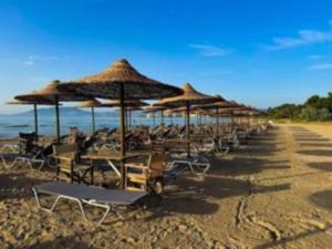 a row of chairs and umbrellas on a beach at Mia Nest in Artemida