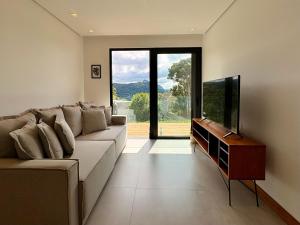 a living room with a couch and a flat screen tv at Casa 08 Monte Boa Vista - Piscina Privativa, Sauna e Ofurô de Imersão in Teresópolis