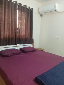 a bedroom with a bed with purple sheets and a window at Akshara Ac 1 bhk in Hinjewadi