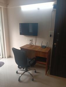 a desk with a chair and a television on a wall at Akshara Ac 1 bhk in Hinjewadi +4 photos
