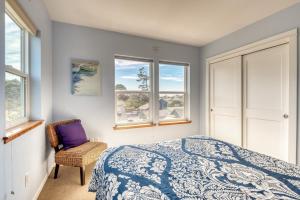 a bedroom with a bed and a chair and windows at Lakeside Haven in Rockaway Beach