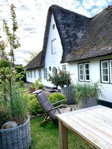 a house with a thatched roof and a wooden table at Inselidyll Alter Friesenhof in Süderende