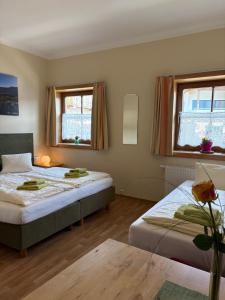 a bedroom with two beds and two windows at Pension Göschlberger in Mondsee
