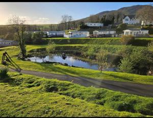 a road in a field with a river and houses at Cocos haven in Ballantrae