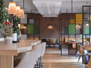 a dining room with a table and chairs with wine bottles at Mercure Auxerre Autoroute du Soleil in Appoigny