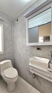 a bathroom with a toilet and a sink and a mirror at Comodidades, modernidad, céntrico in Caracas