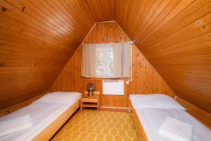 two beds in a wooden room with a window at Chata Jánošík in Terchová +35 photos