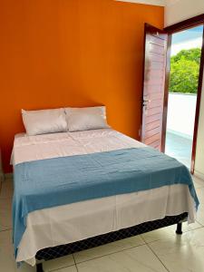 a bed in a room with an orange wall at Refúgio do Mar in Nísia Floresta