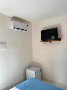 a bedroom with a bed and a tv on the wall at Refúgio do Mar in Nísia Floresta