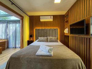a bedroom with a large bed with a tv on the wall at Studios Heaven in Gramado