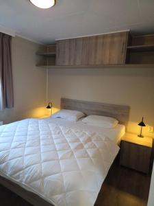 a bedroom with a large white bed with two lamps at de Schelphoeve in Ellemeet