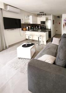a living room with a couch and a kitchen at Studio cosy, Centre Port, Piscine, proche plage in Cap d'Agde