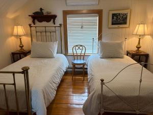 a bedroom with two beds and a chair and a window at Yamachiche P.Q. in Yamachiche