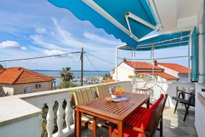 a balcony with a wooden table and chairs with a view of the ocean at Apartment Tea with Sea View in Petrcane