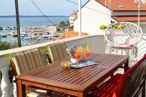a wooden table on a balcony with drinks on it at Apartment Tea with Sea View in Petrcane