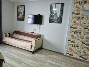 a room with a couch and a tv on a wall at TOWERS Apartament in Batumi