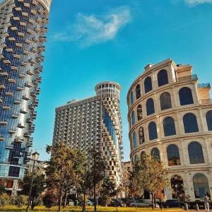 two tall buildings in a city with trees in front at TOWERS Apartament in Batumi