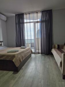 a bedroom with two beds and a large window at TOWERS Apartament in Batumi