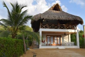 a house with a thatched roof and a palm tree at Cabaña CasaMar Angelica in El Puertón