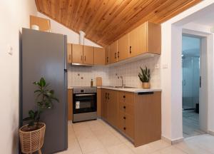 a kitchen with wooden cabinets and a stainless steel refrigerator at Αυλή στην Μαρίνα in Kalamata